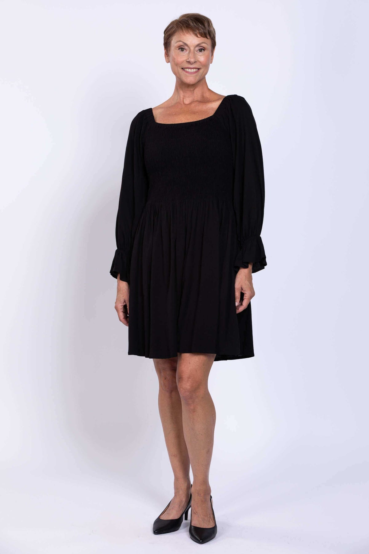 Front view of a woman in a black empire waist dress with long sleeves