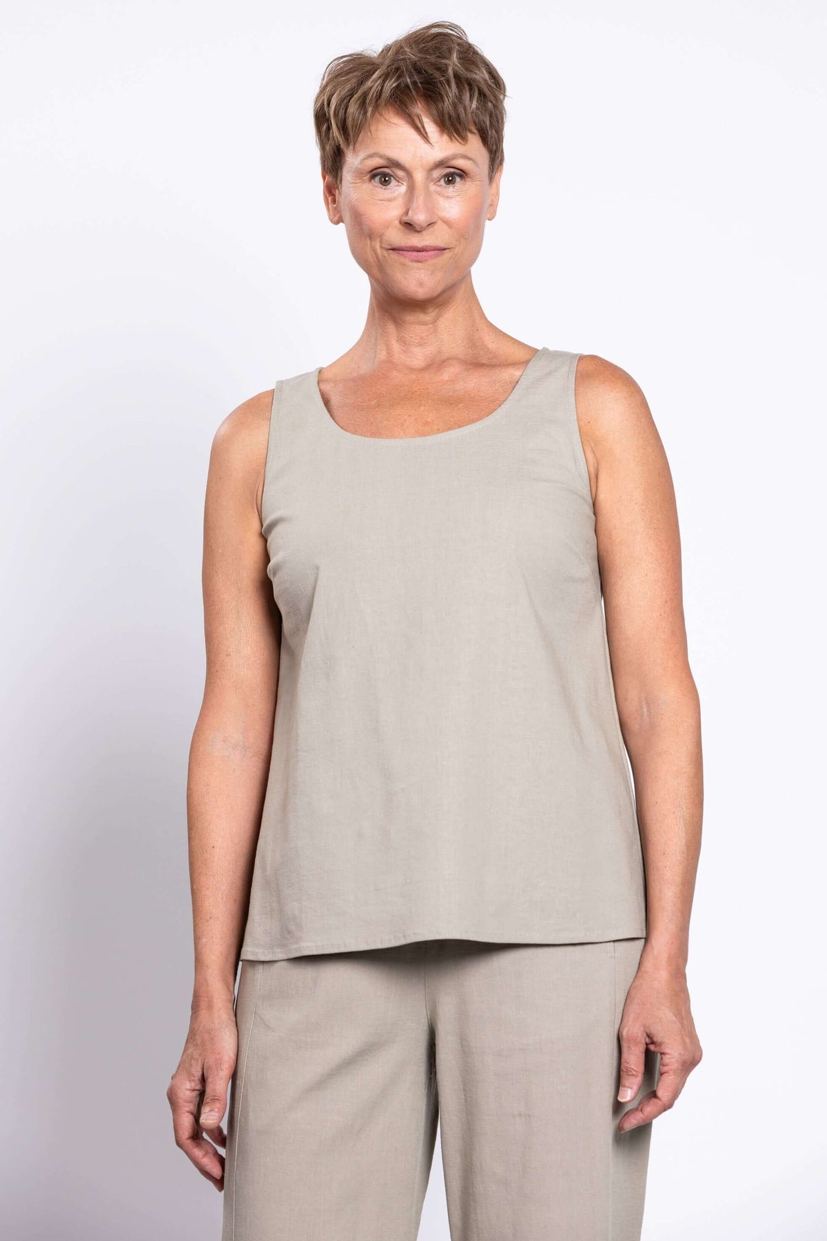 Woman wearing a sleeveless beige tank top and matching pants, front view