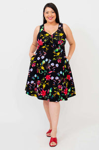 Front view of woman wearing sleeveless black floral fit and flare dress with pockets