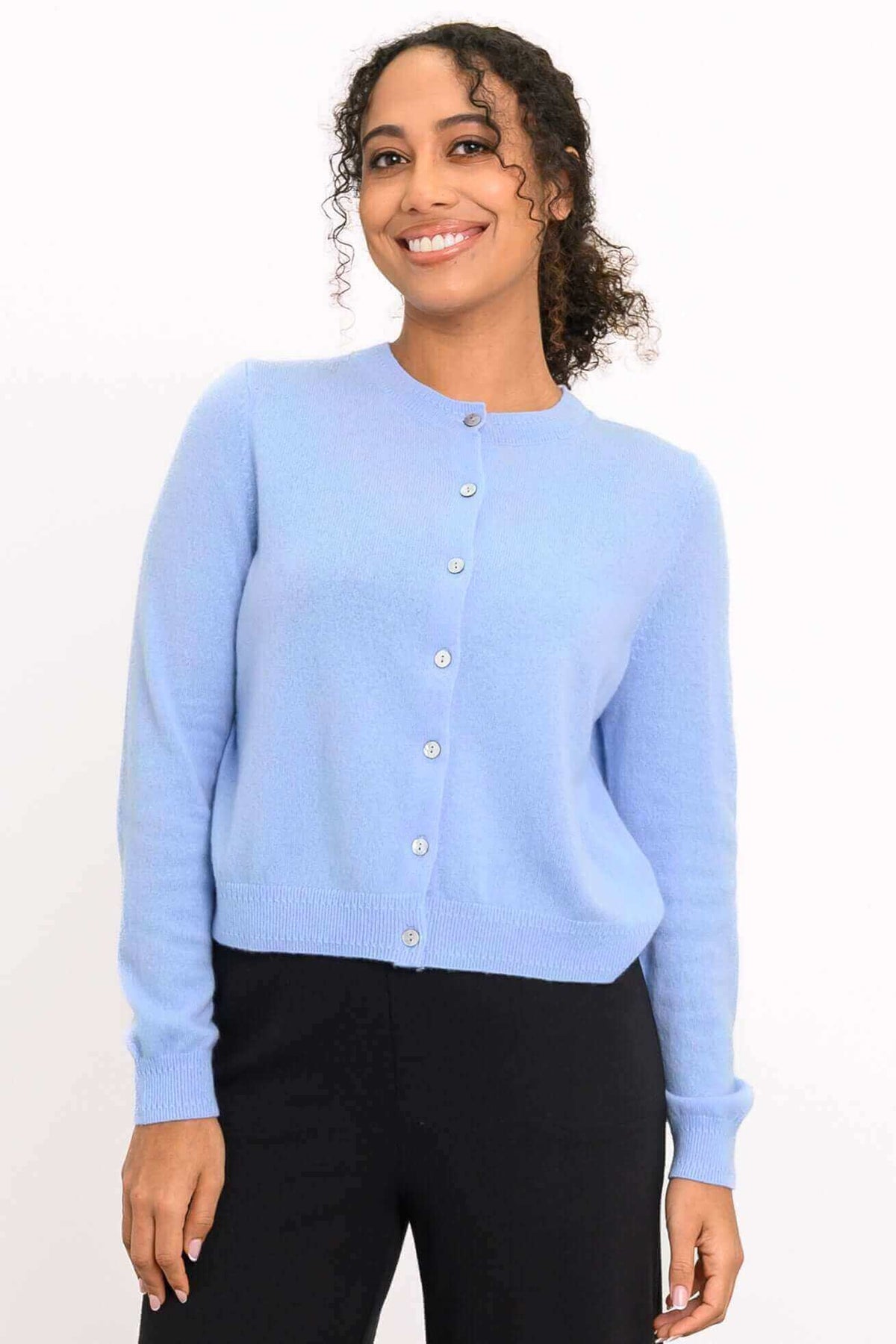 Front view of a woman wearing a light blue cashmere cardigan with black trousers