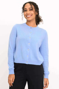 Front view of a woman wearing a light blue cashmere cardigan with black trousers