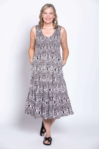Front view of woman wearing sleeveless black and white patterned tiered dress with pockets