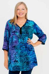 Front view of woman wearing a blue and purple batik print blouse with V-neck and ¾ sleeves