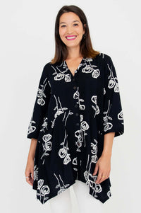 Woman wearing a black button-up tunic with white rose sketch print, front view