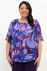 Front view of a woman wearing a purple Water Iris floral blouse with elbow-length sleeves