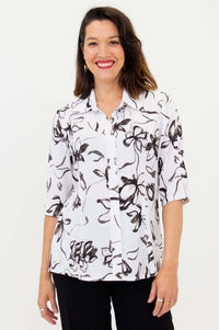 Woman wearing a white blouse with black floral pattern and half sleeves, front view