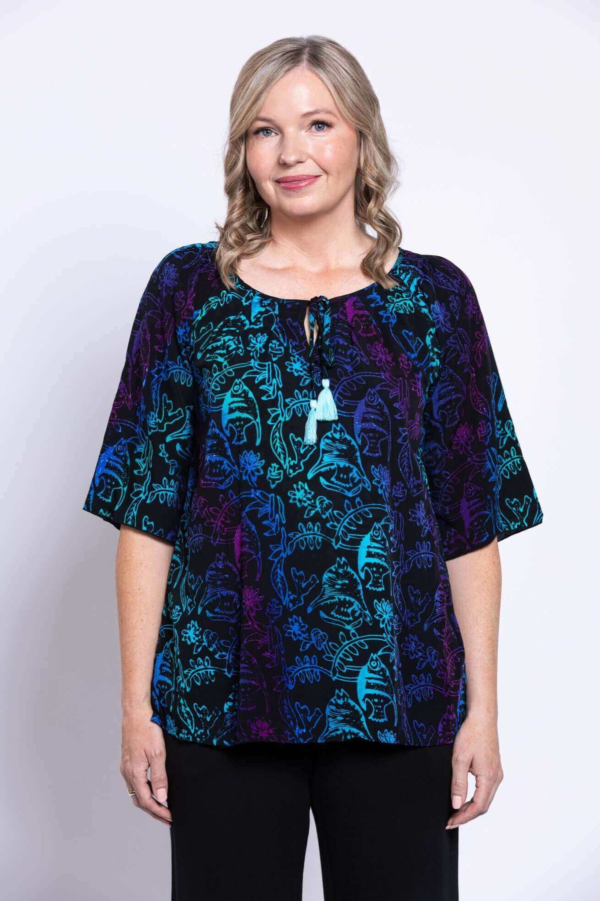 Front view of a woman wearing a Luna Boho Peasant Top with blue and purple print and tie-front detail