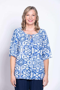 Woman wearing a blue and white patterned peasant top with tie-front detail, front view