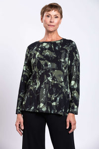Front view of a woman wearing a long sleeve bamboo print top with green and black abstract pattern