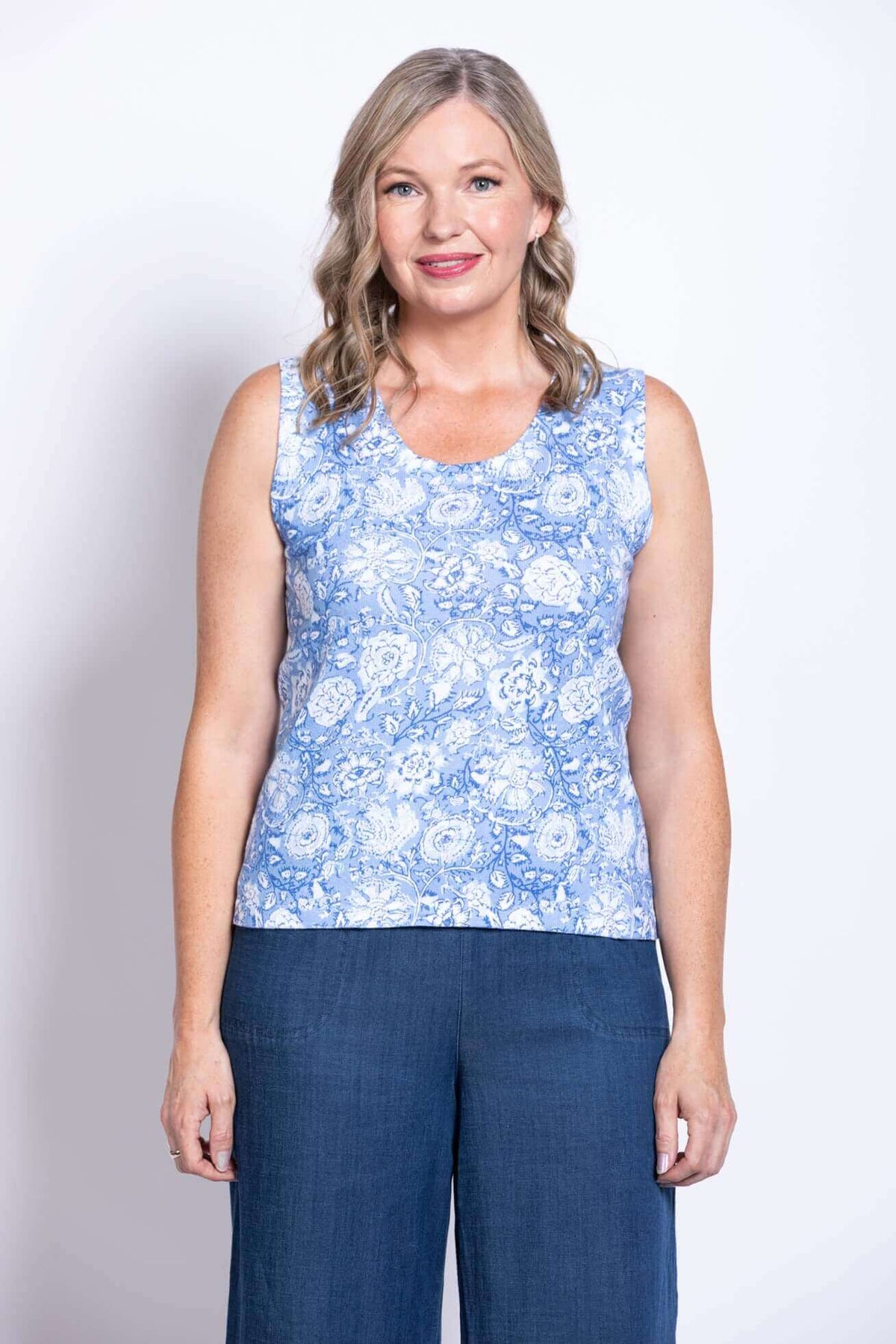 Front view of a woman wearing a blue floral tank top with wide straps