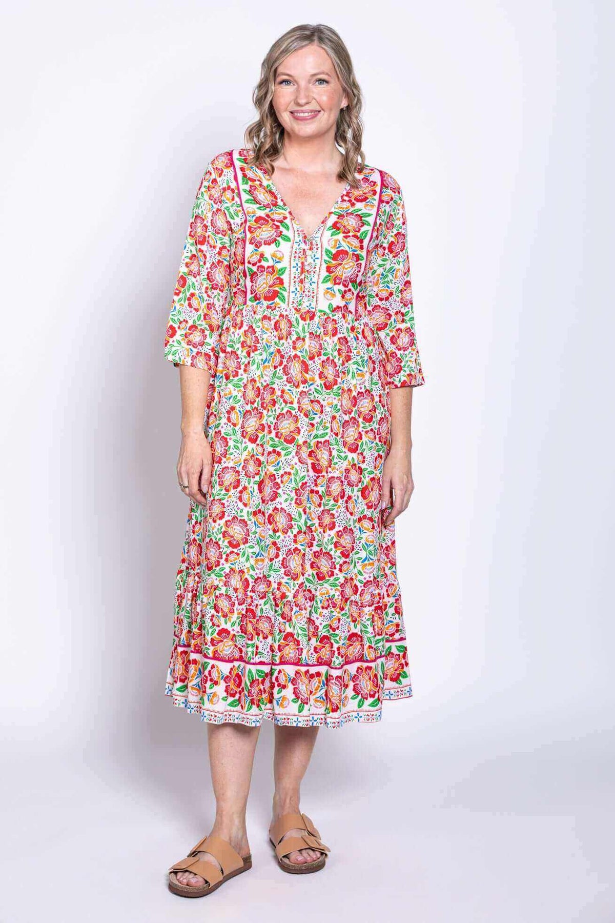 Front view of woman wearing a colorful floral batik midi dress with 3/4 sleeves