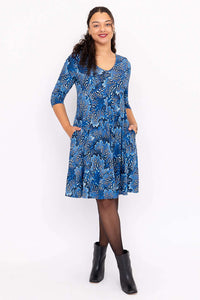 Front view of woman wearing a blue floral fit and flare dress with pockets and black ankle boots