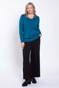 Front view of a woman wearing black wide-leg pants and a teal sweater