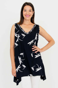 Front view of woman wearing a sleeveless black tunic with white floral print and contrast V-neckline