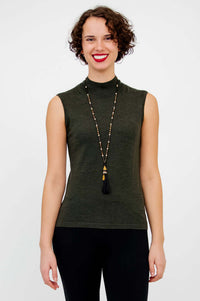Woman wearing sleeveless olive-green mock neck sweater with long necklace, front view