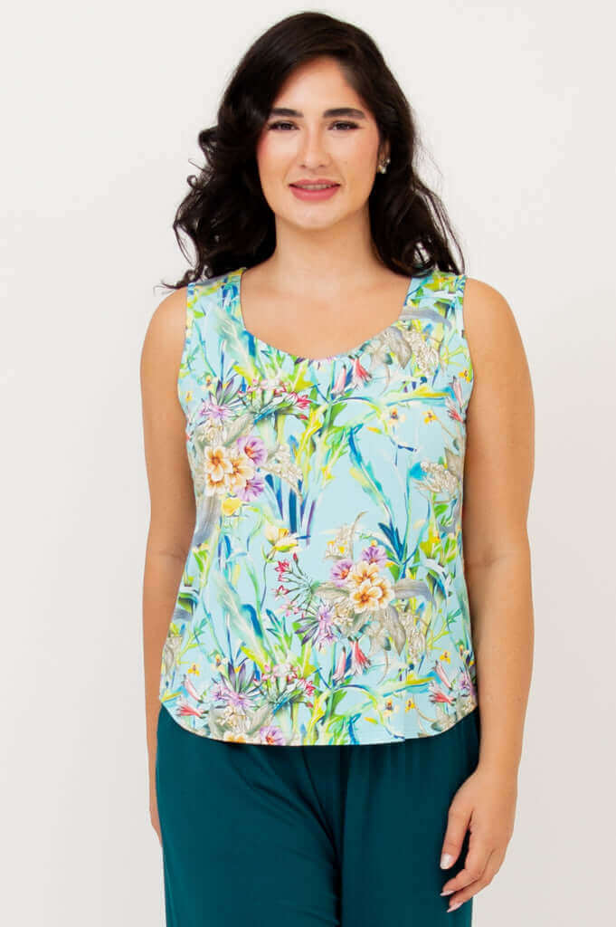 Front view of model wearing Ritzy Tank in tropical floral print with blue background