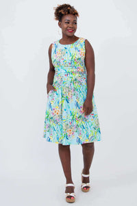 Front view of model in blue floral dress with ruched bodice and hand in pocket