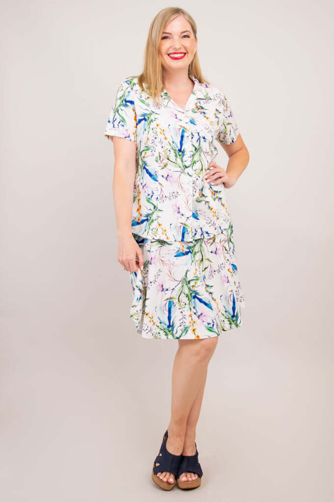Woman in a floral button-up shirt and matching skirt, smiling, front view