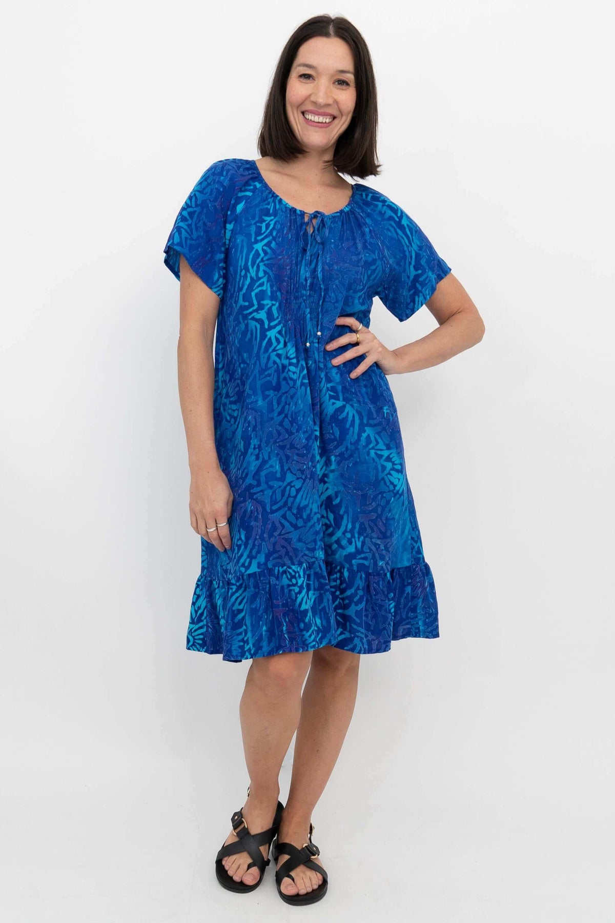 Front view of woman wearing bright blue short sleeve Samoa Dress with ruffle hem