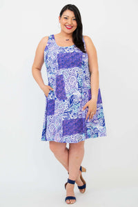 Front view of a woman smiling in a purple patchwork print sleeveless summer dress