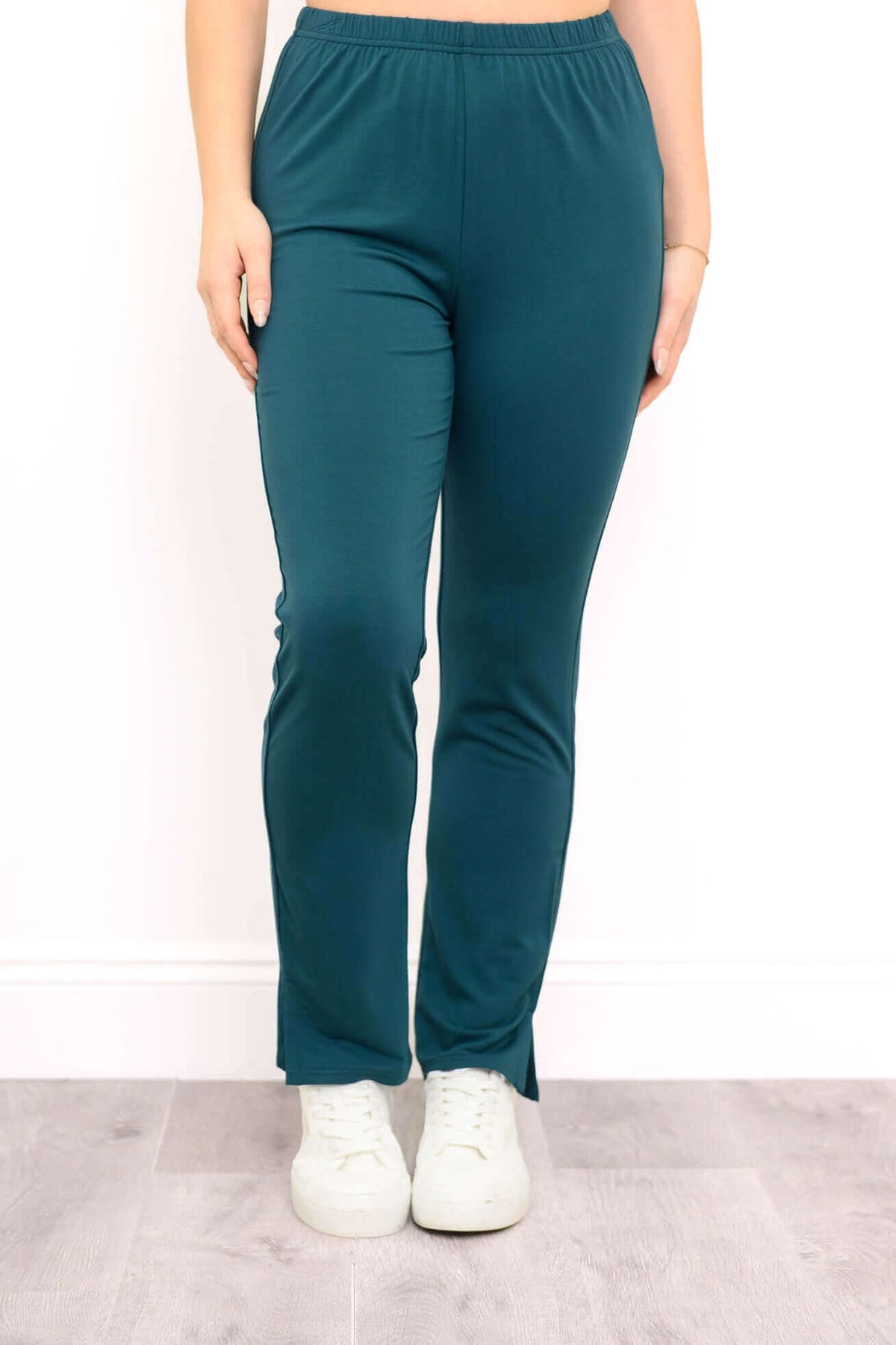 Front view of teal colour pants with ankle slit and sneakers