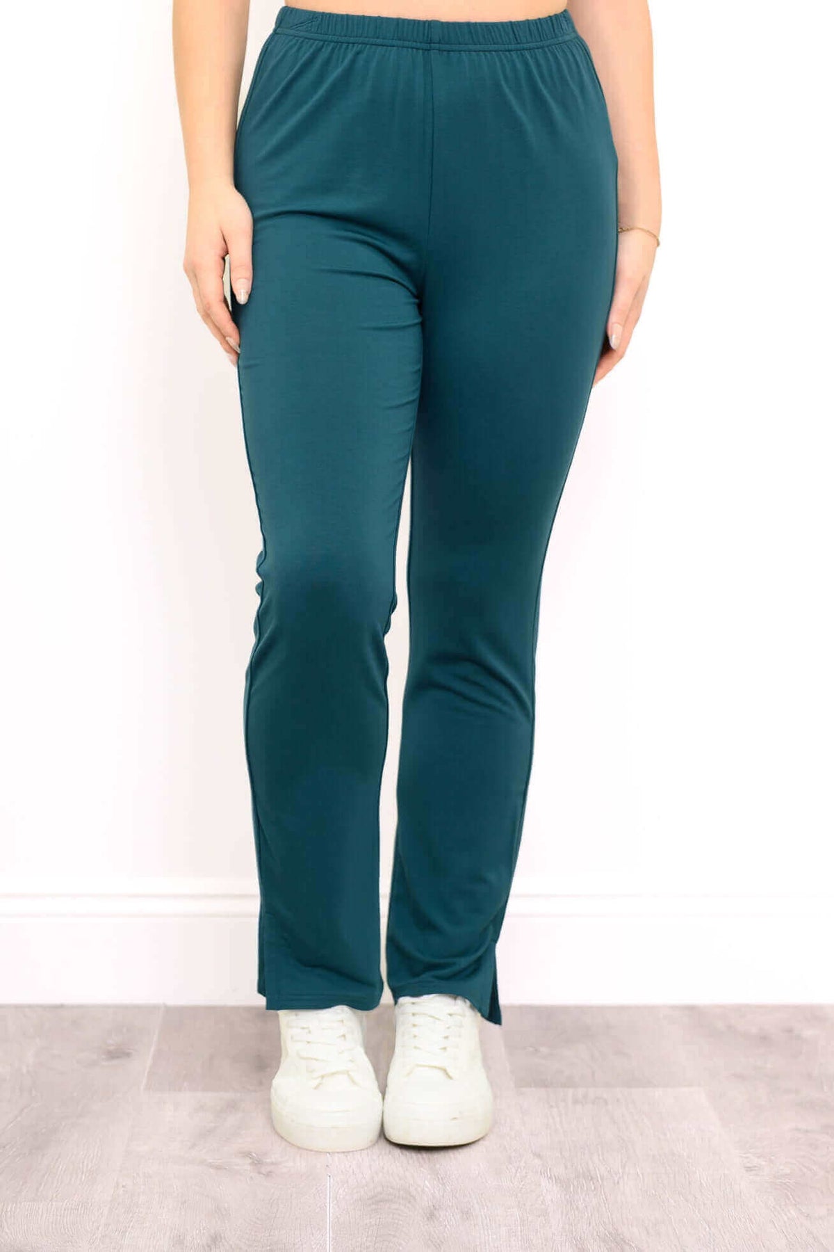 Front view of teal bamboo slim-fit pants with ankle slits and elastic waist, worn with white sneakers