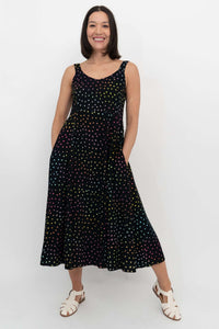 Front view of woman wearing a sleeveless black midi dress with multicolored polka dots