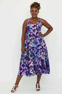 Front view of woman wearing a purple floral empire waist A-line midi dress with pockets