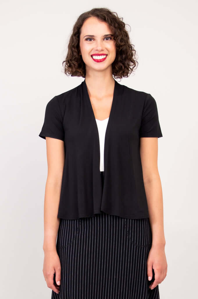 Front view of woman wearing a black short sleeve open jacket over a white top
