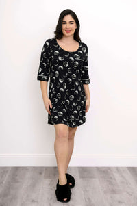 Front view of a woman in a moon phase patterned black sleepshirt with piping details