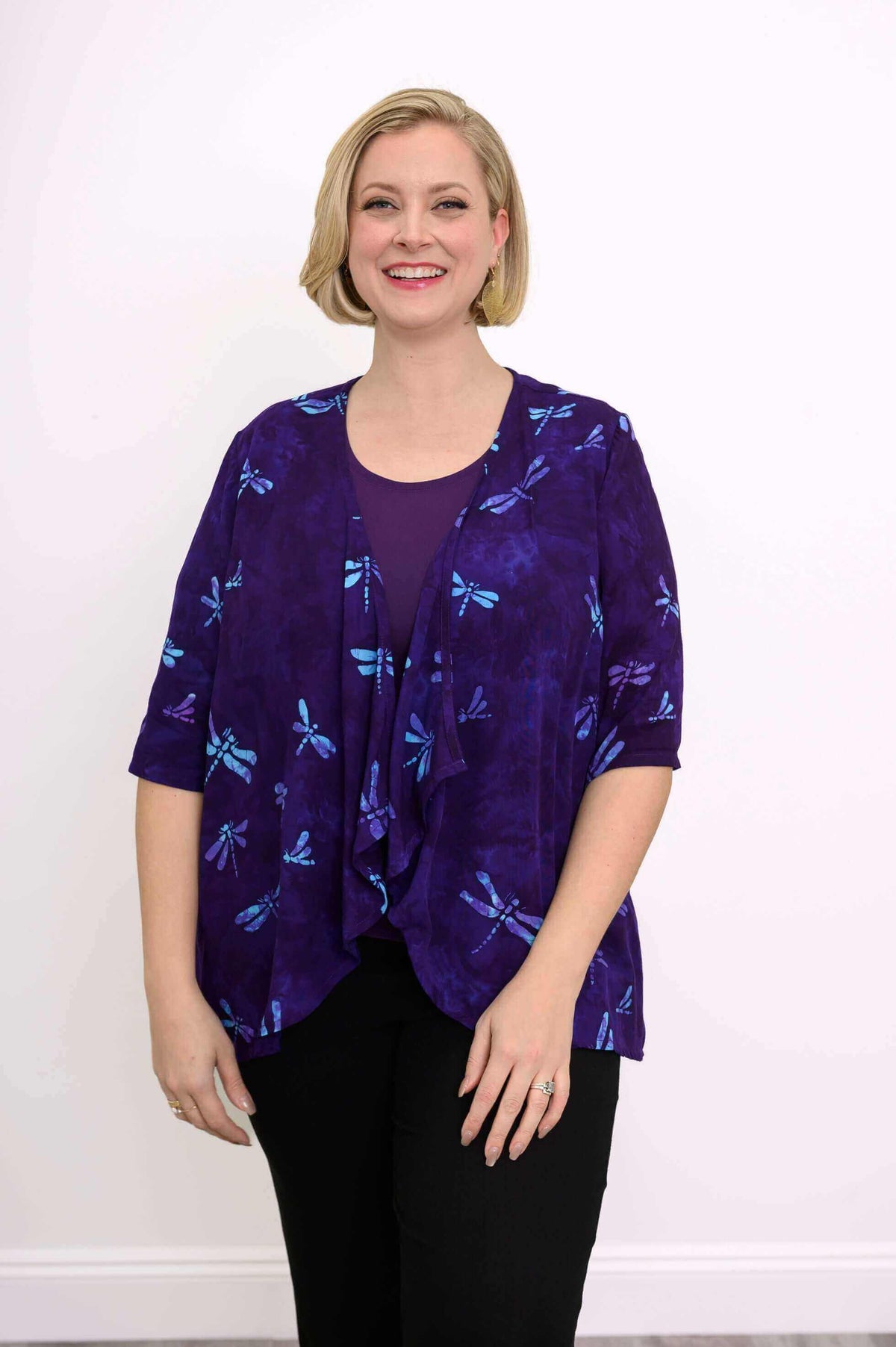 Woman wearing a purple jacket with blue dragonfly prints, paired with a purple top and black pants