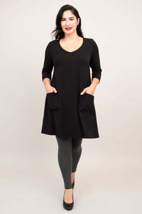 Model walking forward in black A-line tunic dress with hands in pockets