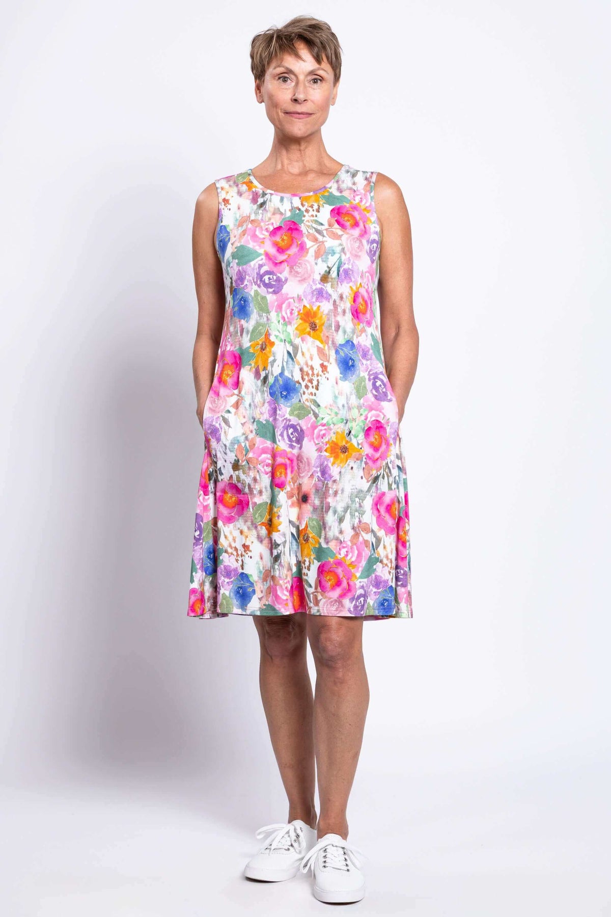 Front view of woman wearing a sleeveless floral dress with pockets