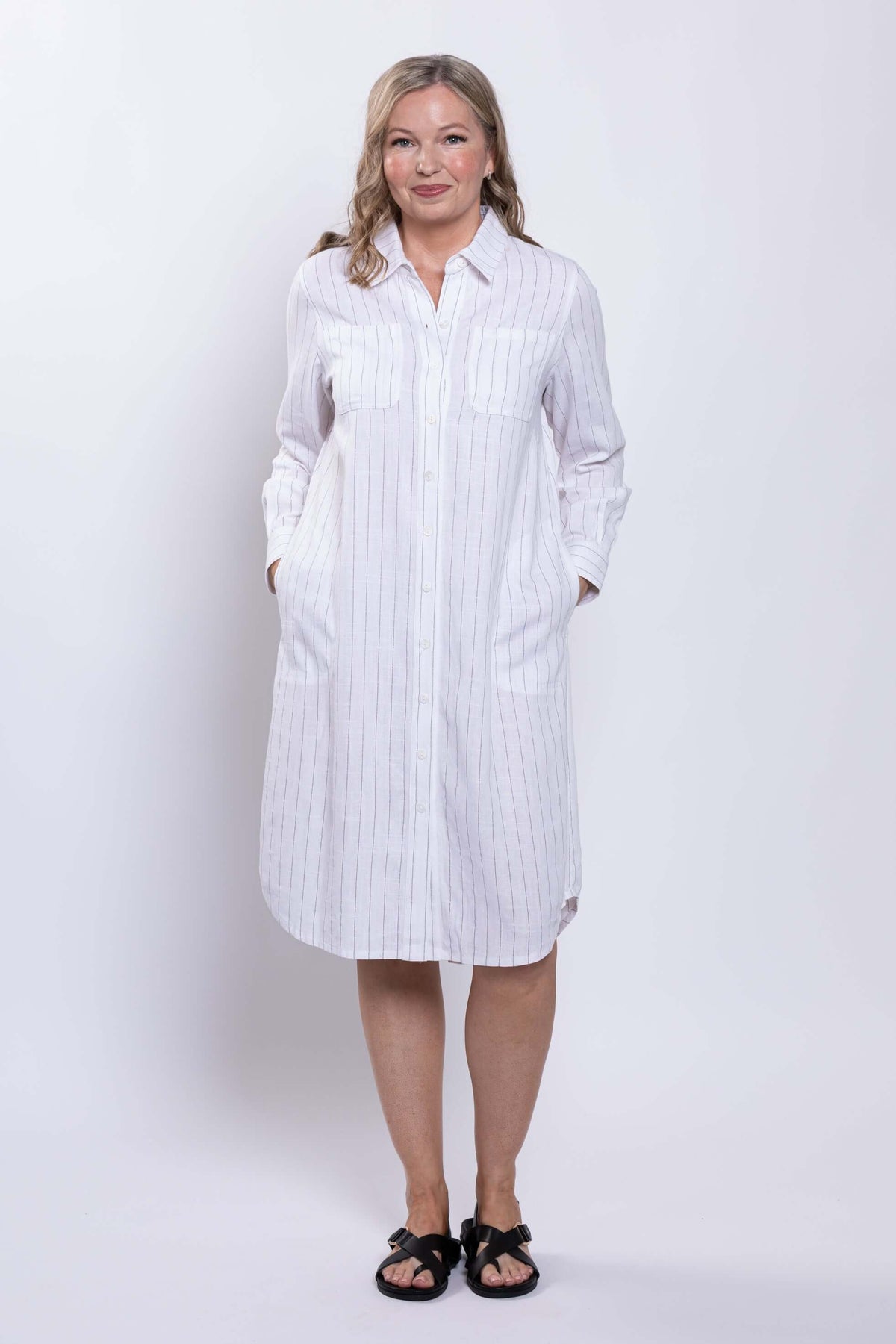Front view of a woman in a white striped button-down shirt dress with pockets