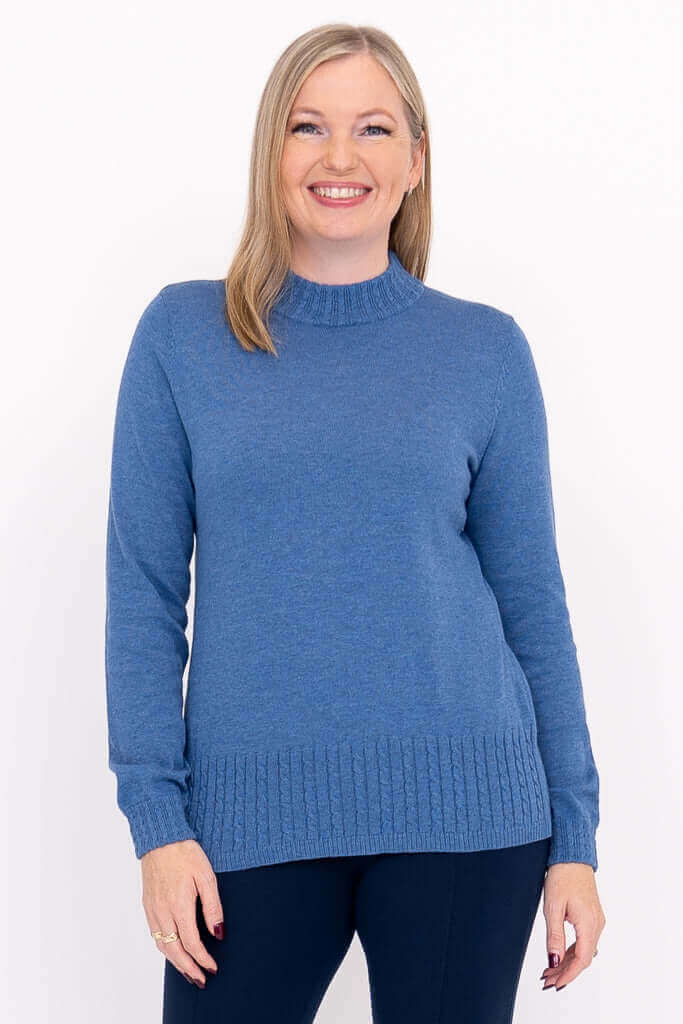 Front view of a woman wearing a blue mock neck cable knit sweater