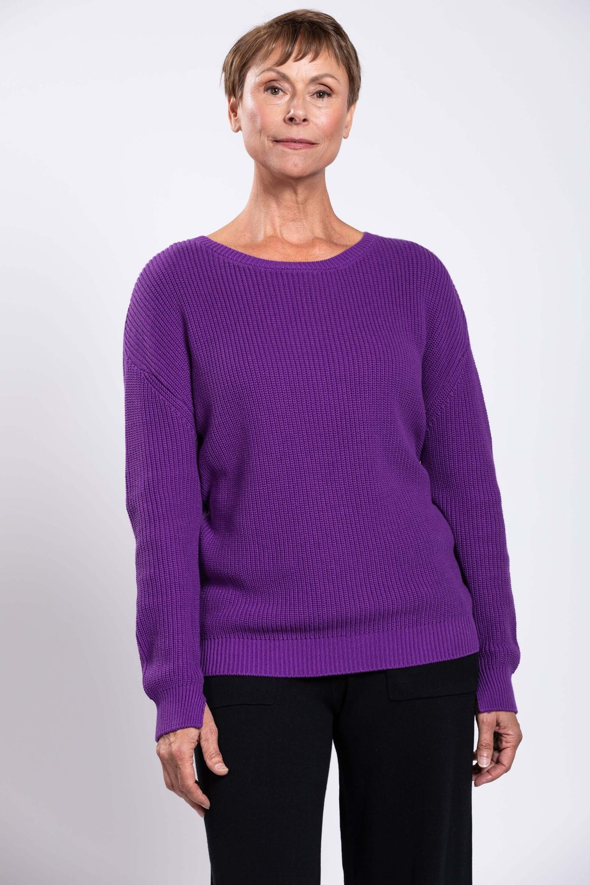 Front view of a woman wearing a vibrant purple shaker stitch sweater
