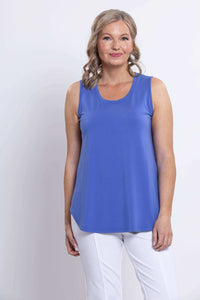 Front view of a woman wearing an azure blue sleeveless bamboo tank top and white pants
