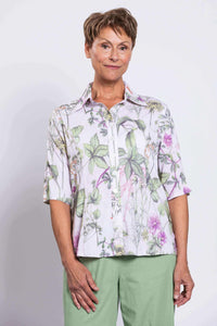 Front view of a woman wearing a botanical print bamboo-linen blouse with green pants