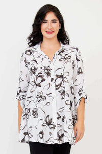 Woman wearing a white oversized tunic with black floral print, front view