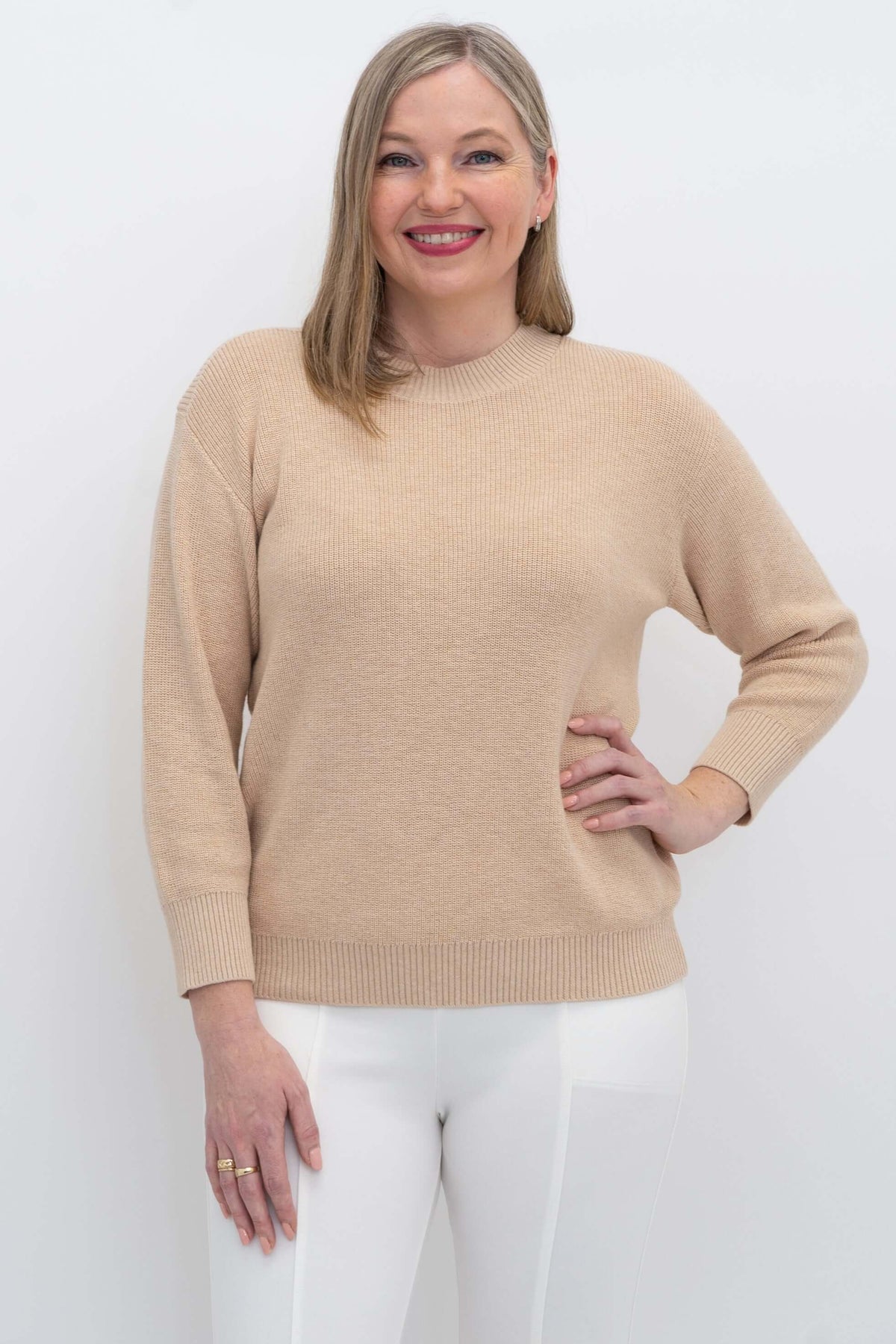 Woman wearing a beige crew neck sweater with drop shoulders, close-up front view