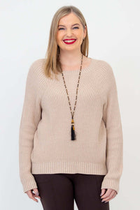 Front view of a woman wearing a beige knit Davis Sweater over brown pants