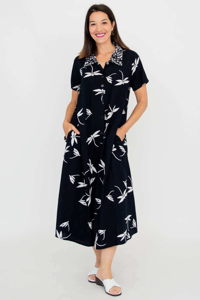 Front view of model wearing a black A-line short sleeve dress with white floral pattern