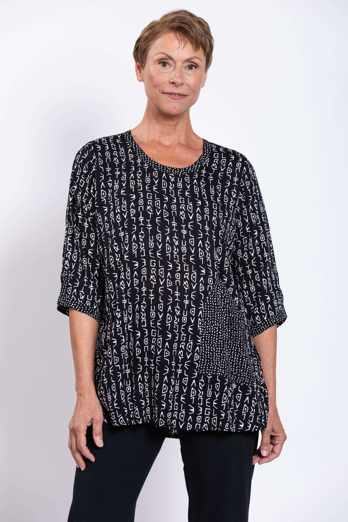 Front view of a woman wearing a black and white abstract print blouse with scoop neckline
