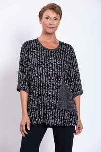Front view of a woman wearing a black and white abstract print blouse with scoop neckline