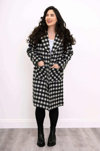 Front view of a woman wearing a black and white check wool coat with patch pockets