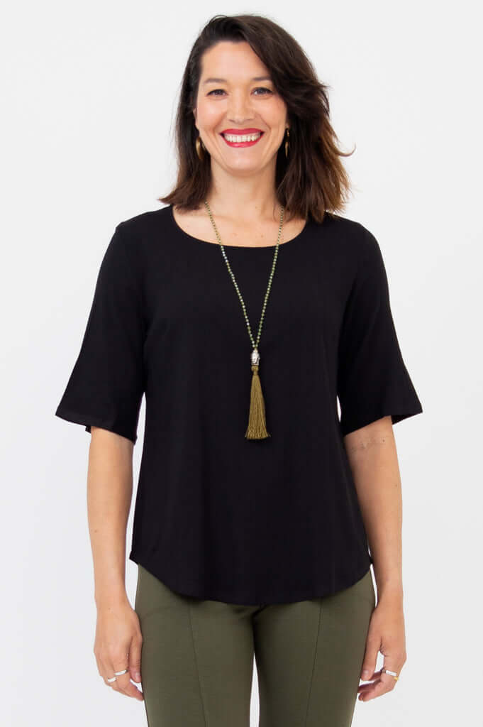 Front view of woman wearing black blouse with elbow sleeves and scoop neckline