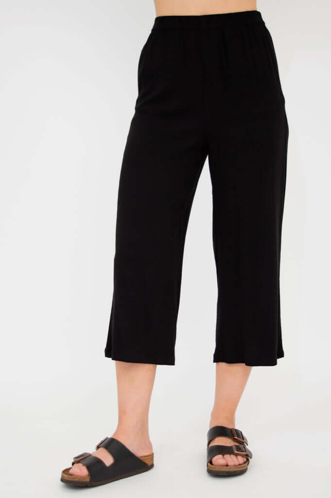 Front view of model wearing black capri pants with elastic waistband