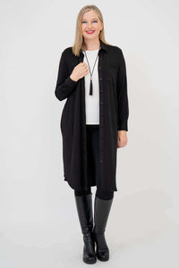 Front view of woman in a black duster coat with chest pockets, hands relaxed, white shirt underneath
