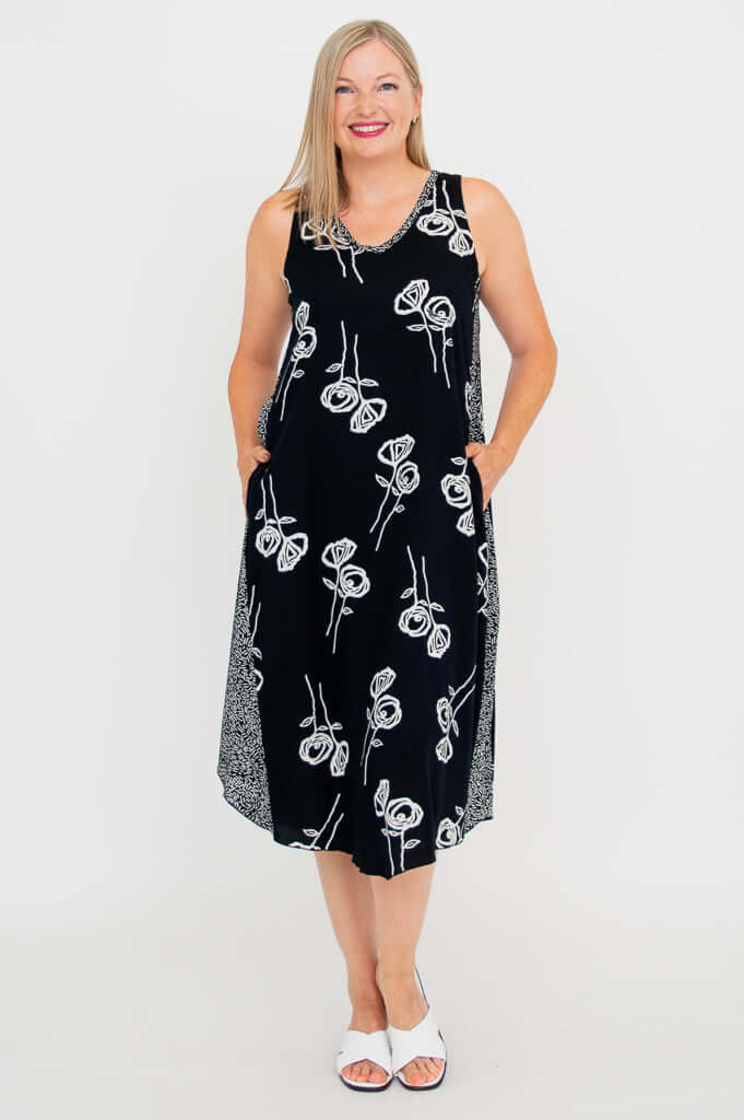 Woman smiling in black midi tank dress with white floral design, front view