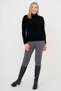 Front view of woman in black mock neck sweater, grey pants, and tall boots